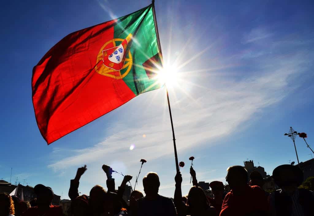 A Crowd on the Street with a Portuguese Flag and Flowers